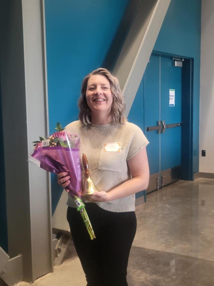 Secretary Pauline Spencer with flowers and a bell.