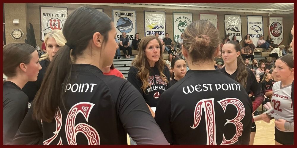 Mrs. Wheeler and the assistant coach huddling with the volleyball team during a game.