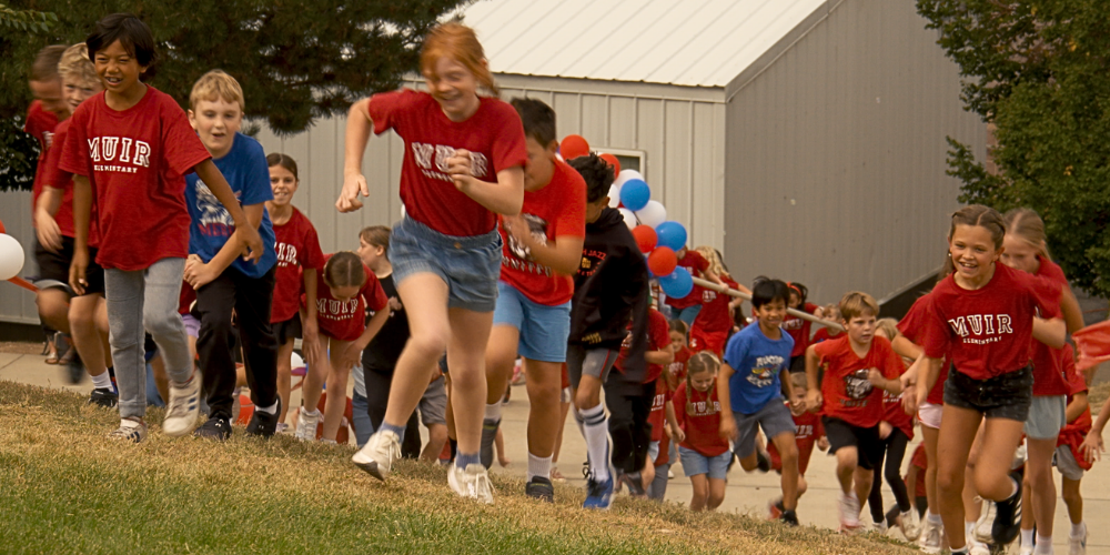 Students running up a hill smiling.