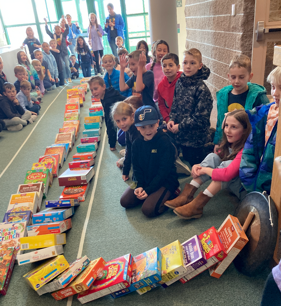 students sitting in the hallway watching ceral boxes tumble like dominos 