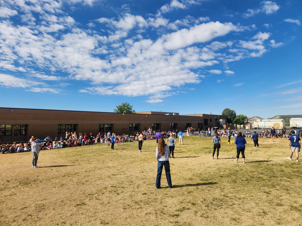 Students and Staff on the playground playing kickball.