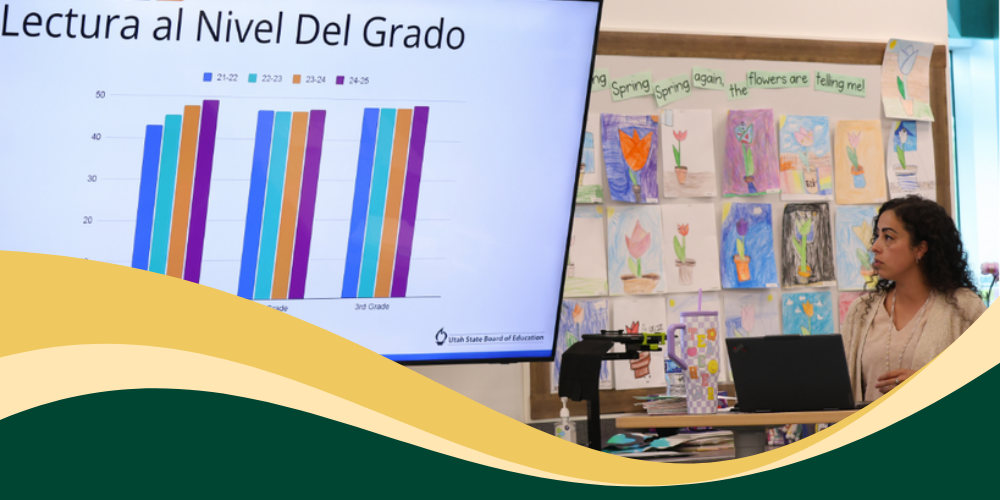 Myra Suarez gives a presentation in Spanish during Bountiful Elementary's Literacy Night, she is speaking beside a screen displaying reading growth data for families.