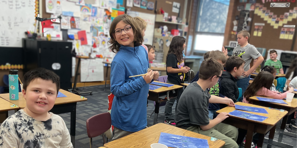 Fourth grade students are visiting a second grade class. They are working with the second graders on an art project, making a winter scene. 