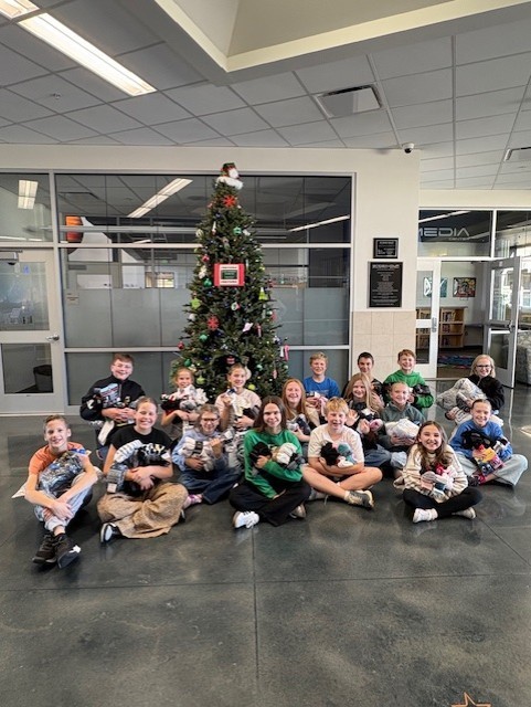 Students holding sock donations in fron of a Christmas tree