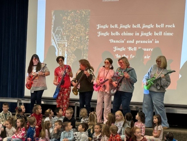 teachers holding guitars singing to a Christmas song.