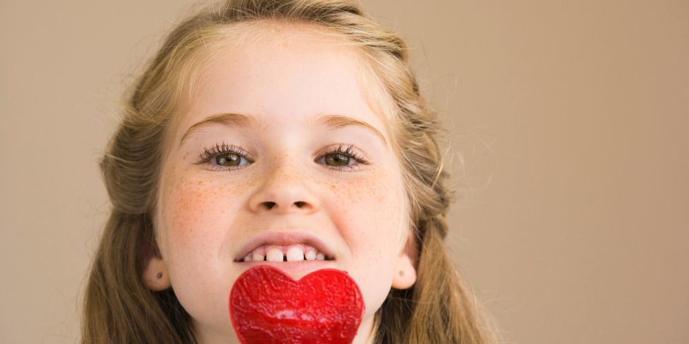 Photo of a girl and a red heart sucker