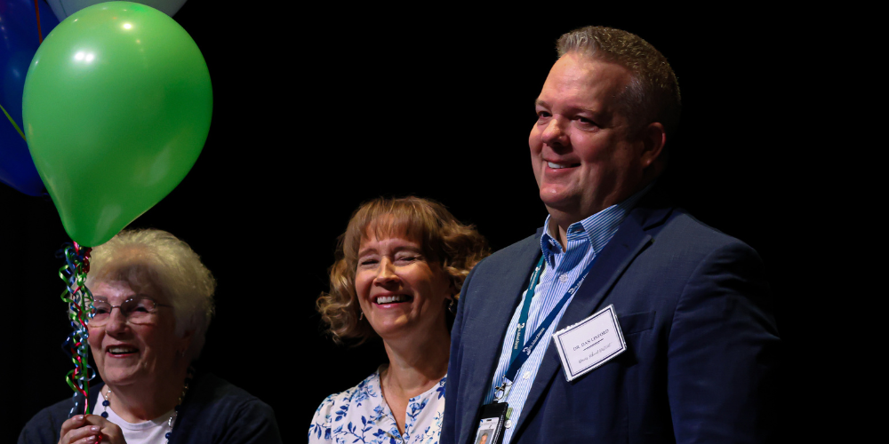 Superintendent Dr. Dan Linford, his wife and his mother smiling.