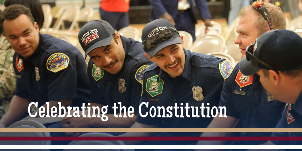 Firefighters smiling and looking at each other with the words "celebrating the constitution" along the bottom of the image. 