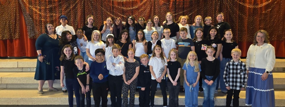 Meadowbrook choir students on the stage steps with two choir directors.