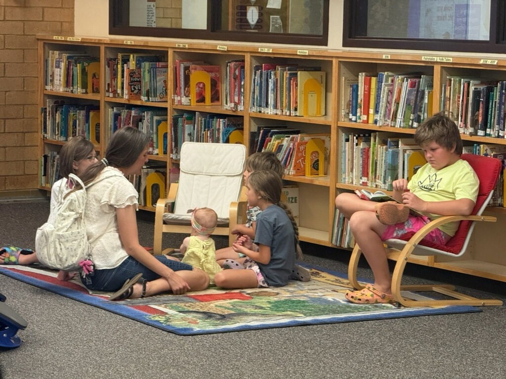 Familiy reading together in the library during summer library hours at Farmington Elementary