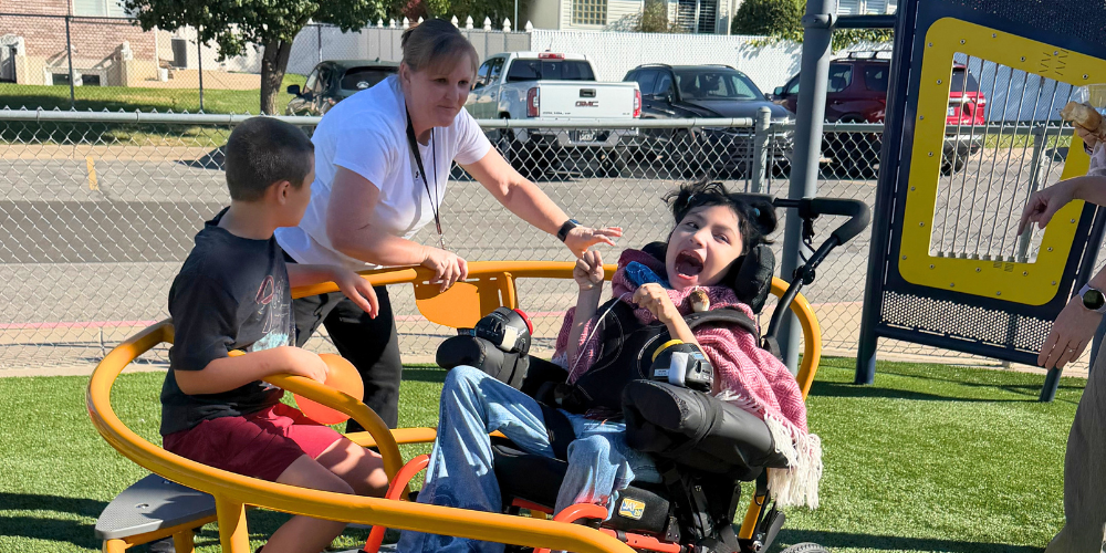 Students play on the all abilities playground equipment