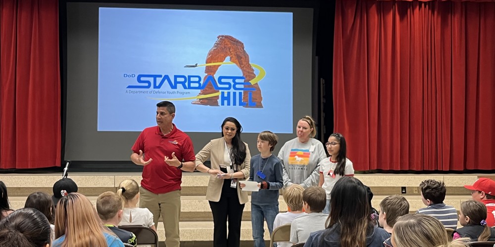students at starbase graduation. A man in a red shirt standing next to two teachers and two students