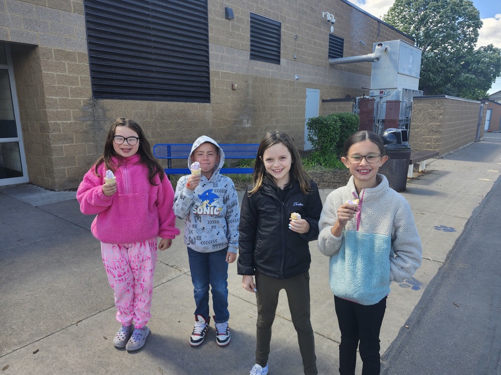 Four 3rd grade students standing outside with ice cream cones.