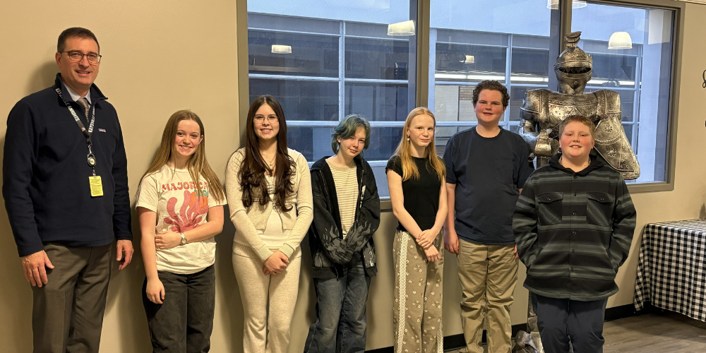 image of 6 students and a principal standing in front of a knight statue.