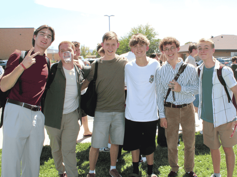 students smiling standing behind the school with backpacks
