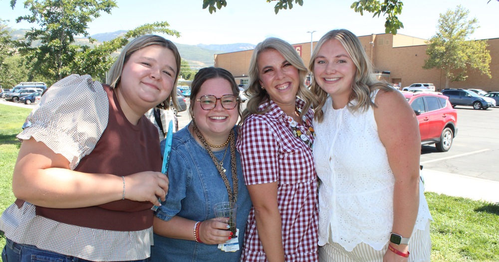 Four Viewmont High School teachers smile together outdoors in front of the school building and parking lot.