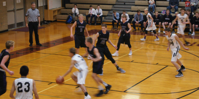 Boys playing basketball in black and white uniforms in school gym