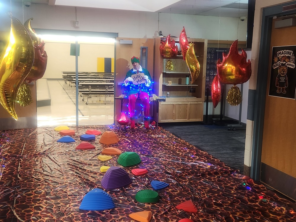 Pinky wrapped in christmas lights with a sign that says Help me with a floor of lava and stepping stones.