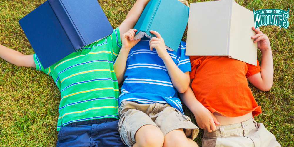 Kids laying on grass with books covering their faces