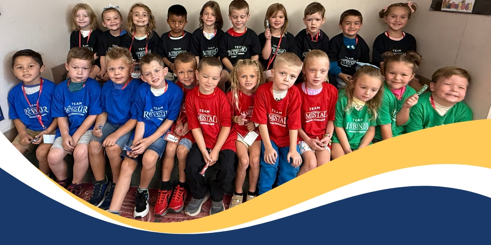 A group of kindergarteners pose for a picture wearing their new house shirts.