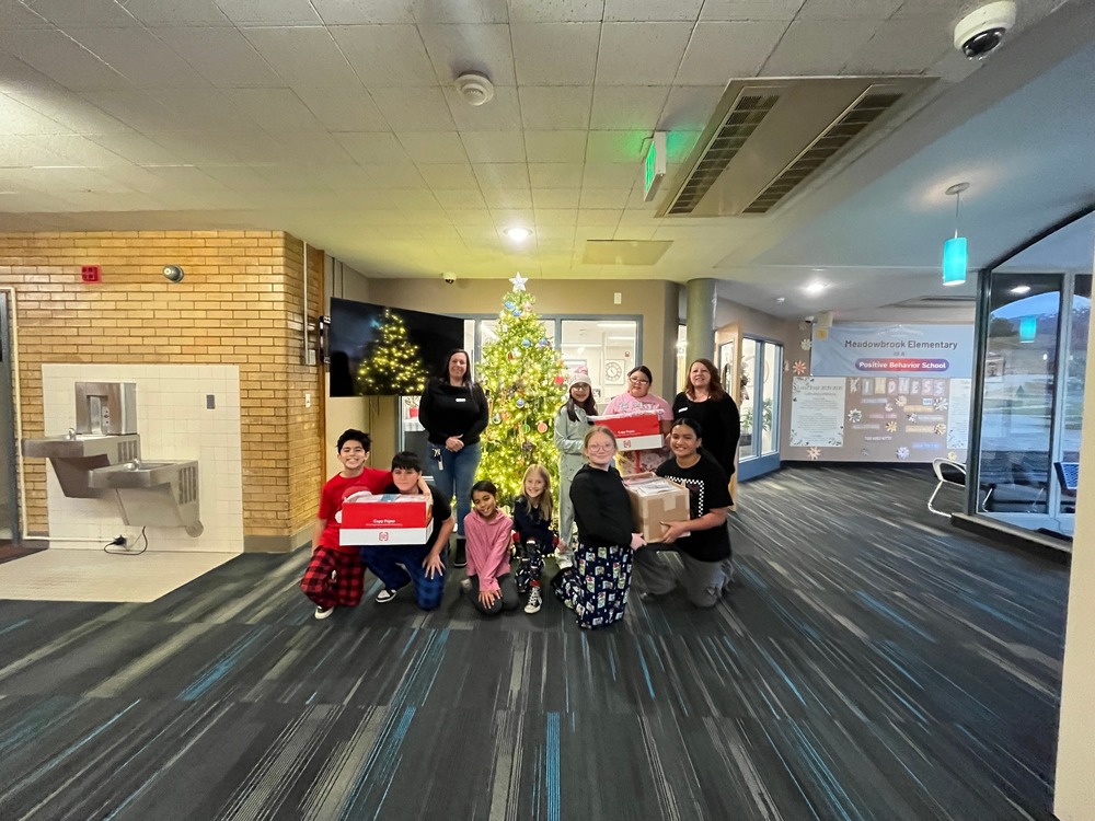 5th grade students in front of a christmas tree with the scarfs they made to donate to unhoused people in Utah