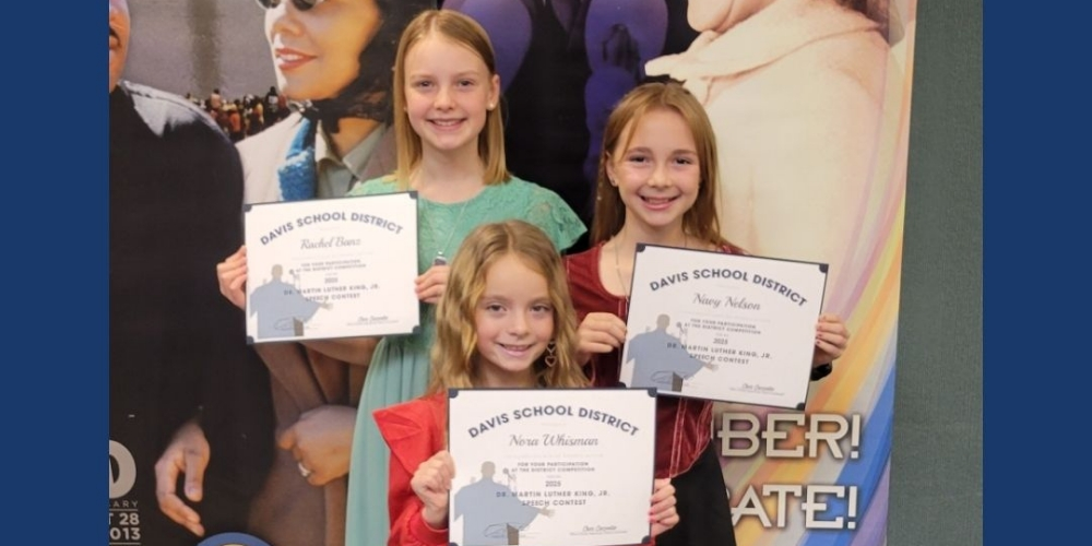 Students holding certificates standing in front of an MLK backdrop. 