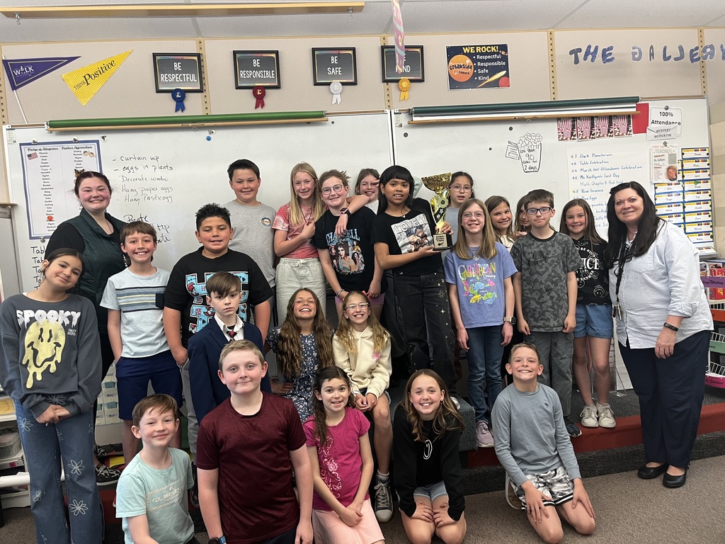 students in classroom with teacher holding a trophy