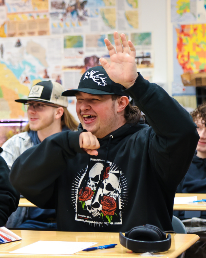 A student excitedly raises his hand in class.