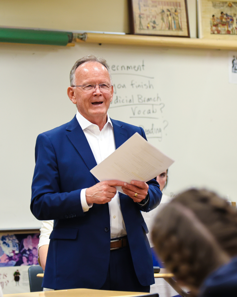 Stuart Adams smiling while talking to high school students.