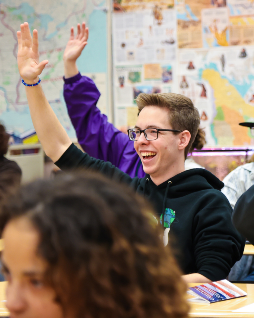 A student excitedly raises his hand in class.