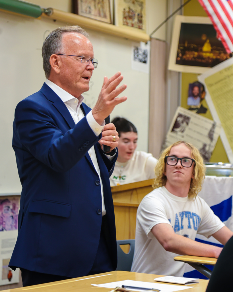 Utah Senate President Stuart Adams holding his hand up while talking to a group of high school students.