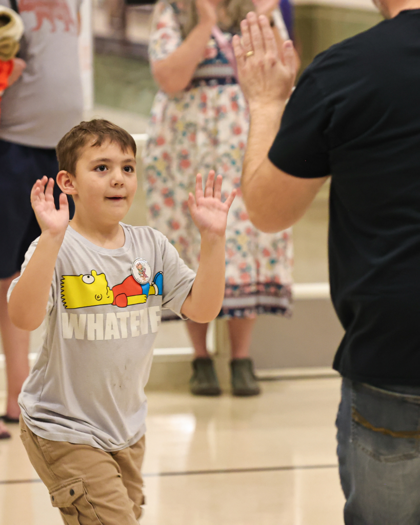 A student holds up his hands getting ready to high five a parent.