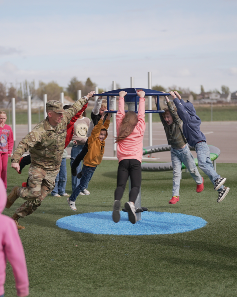 A soldier spins students fast during recess.
