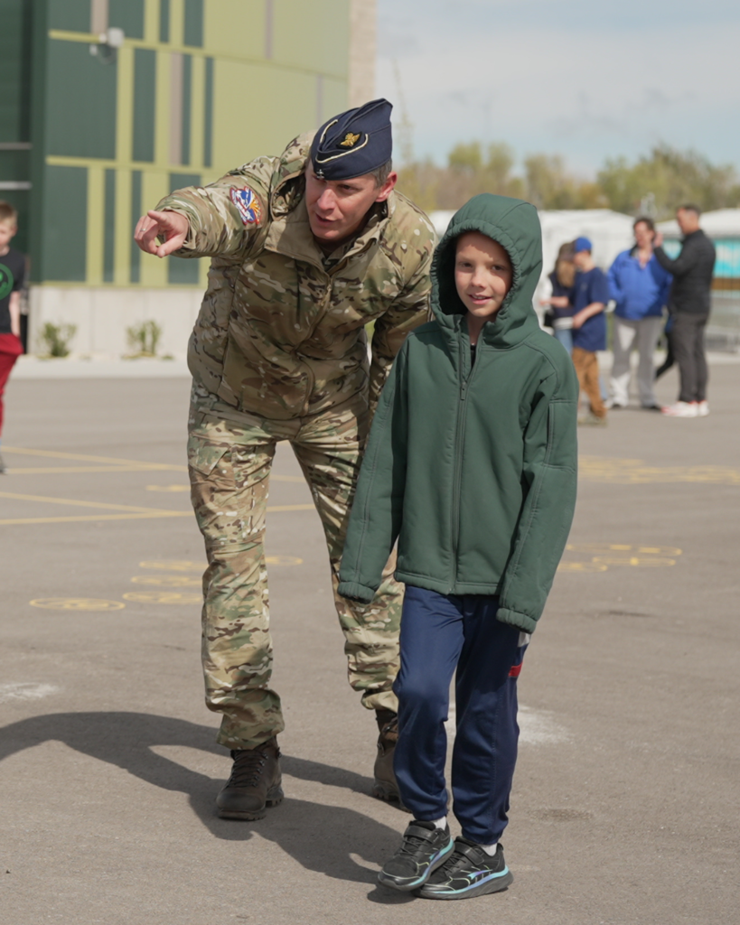 A student smiles as a soldier points to the left.