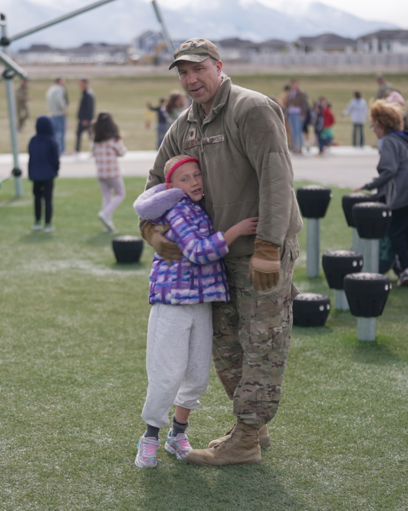 A soldier hugs a student during recess.