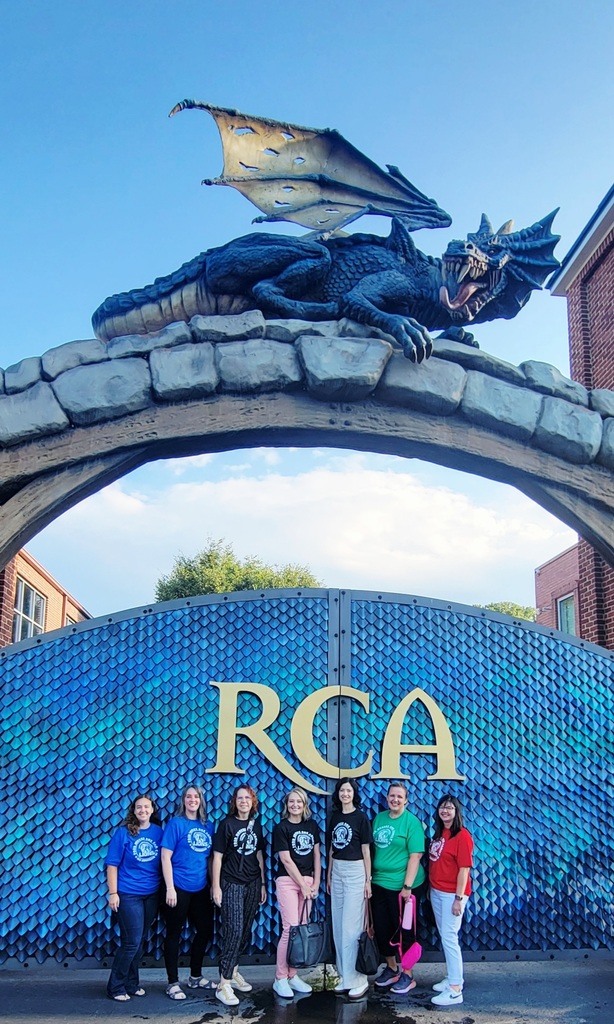 Lakeside Elementary staff members posing in front of the Ron Clark Academy front gate with a dragon sitting at the top of the gates.