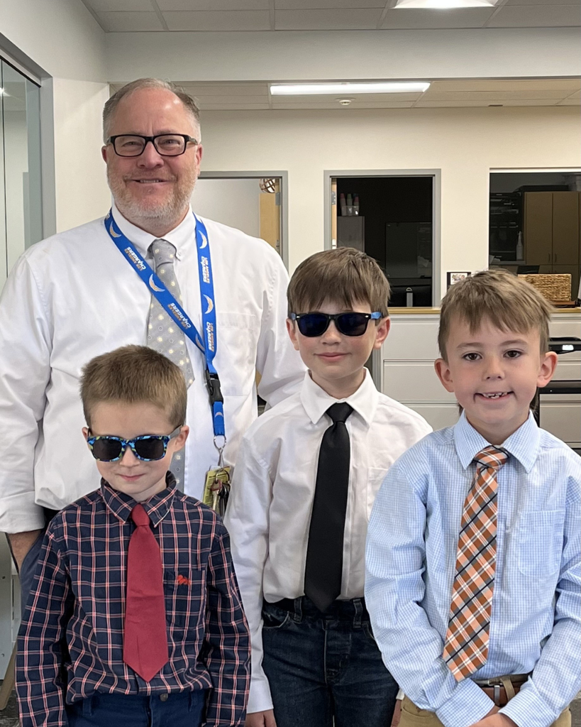 A photo of a principal and three young students from the school who are dressed up in a shirt, tie and glasses to match their principal.