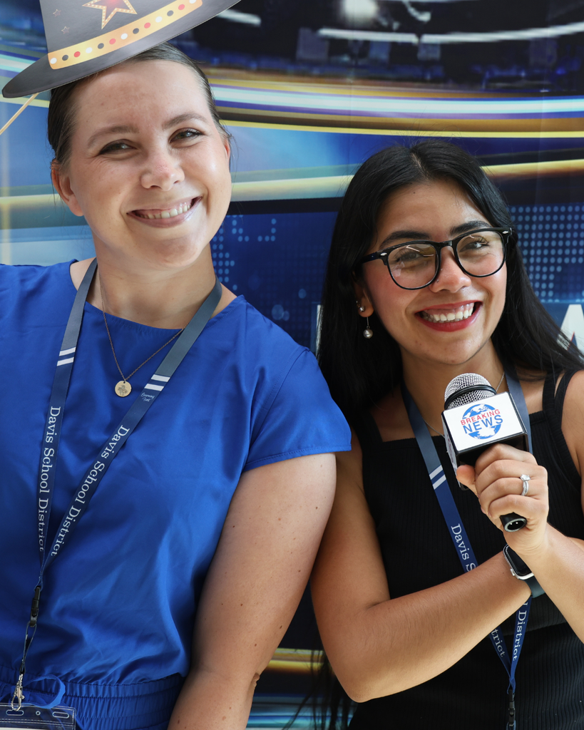 Two new educators smiling and having fun. One is holding a news anchor mic and the other is holding red smiling lips.