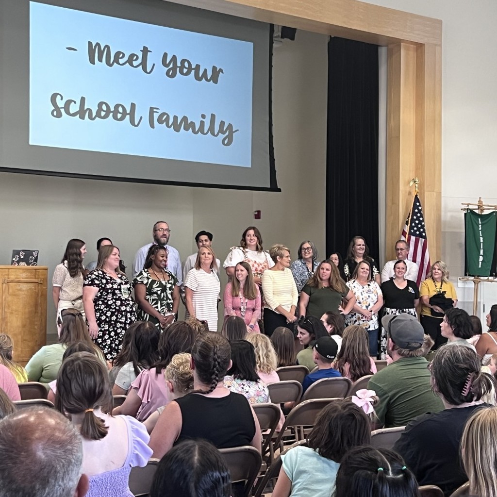 Doxeys staff standing on stage and being introduced to parents and students at back to school night.