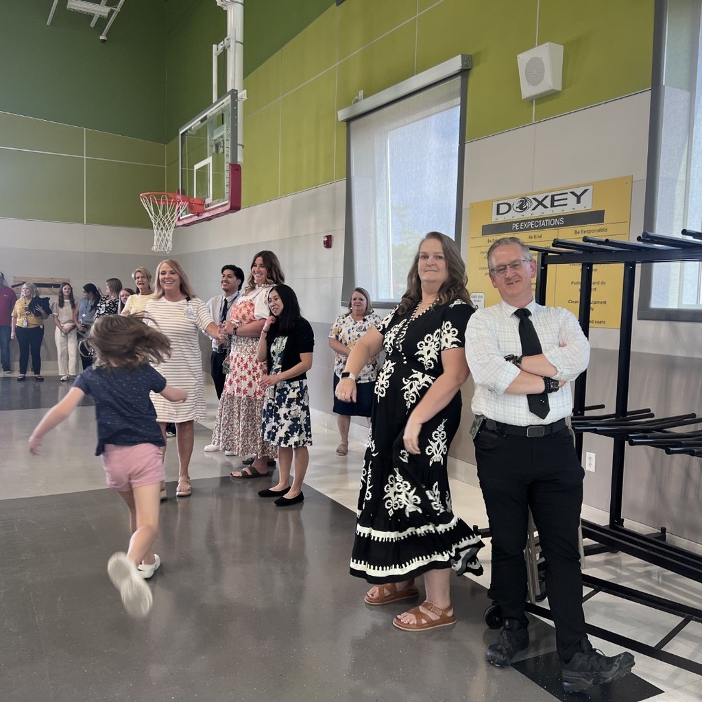 Staff standing off to the side of back to school nights presentations as parents and students enter the gym.