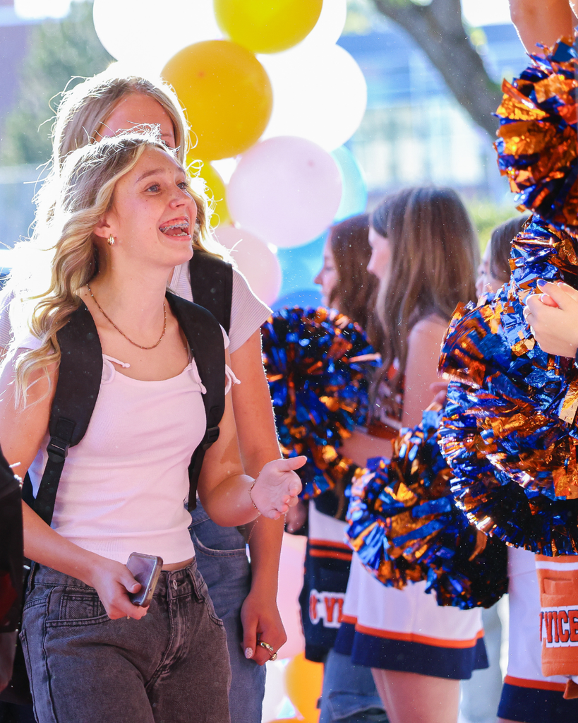 Students smile and talk to chewerleaders as they enter the school on their first day.