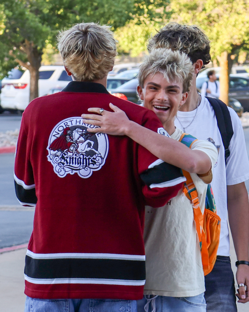 Two friends side-hug on the first day of school.