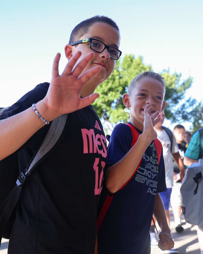 Two students waving at the camera.