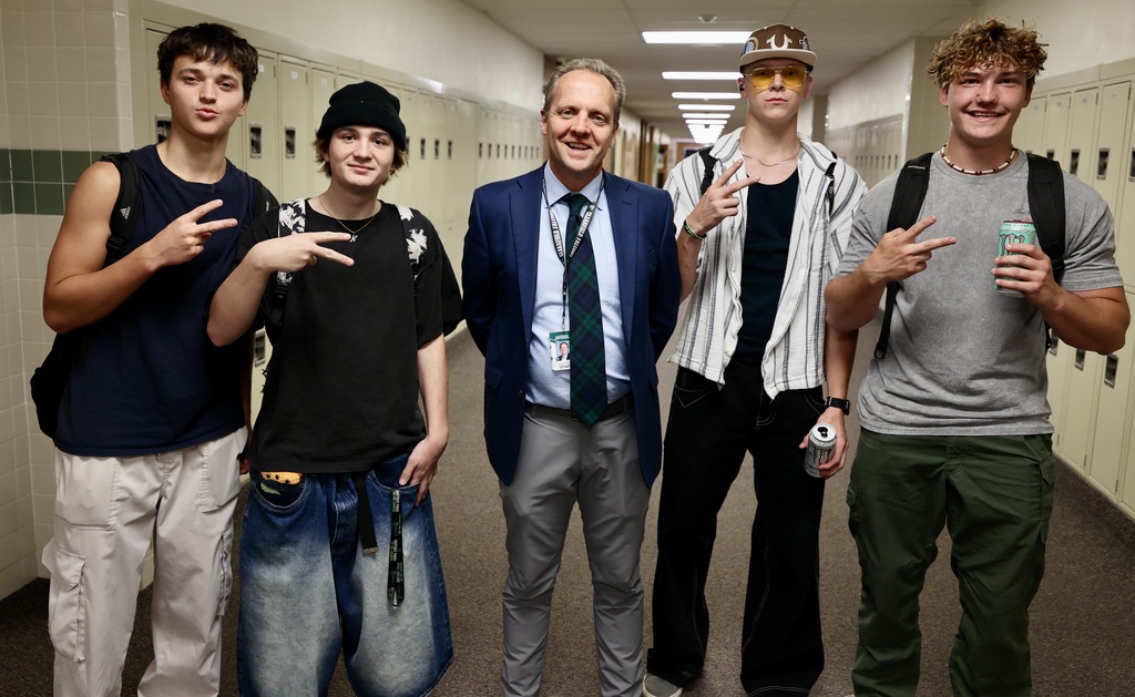A principal smiles with four students.