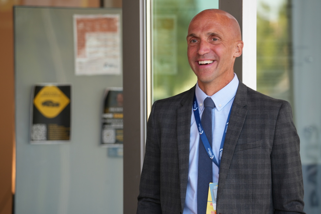 A principal smiles with a half open mouth.