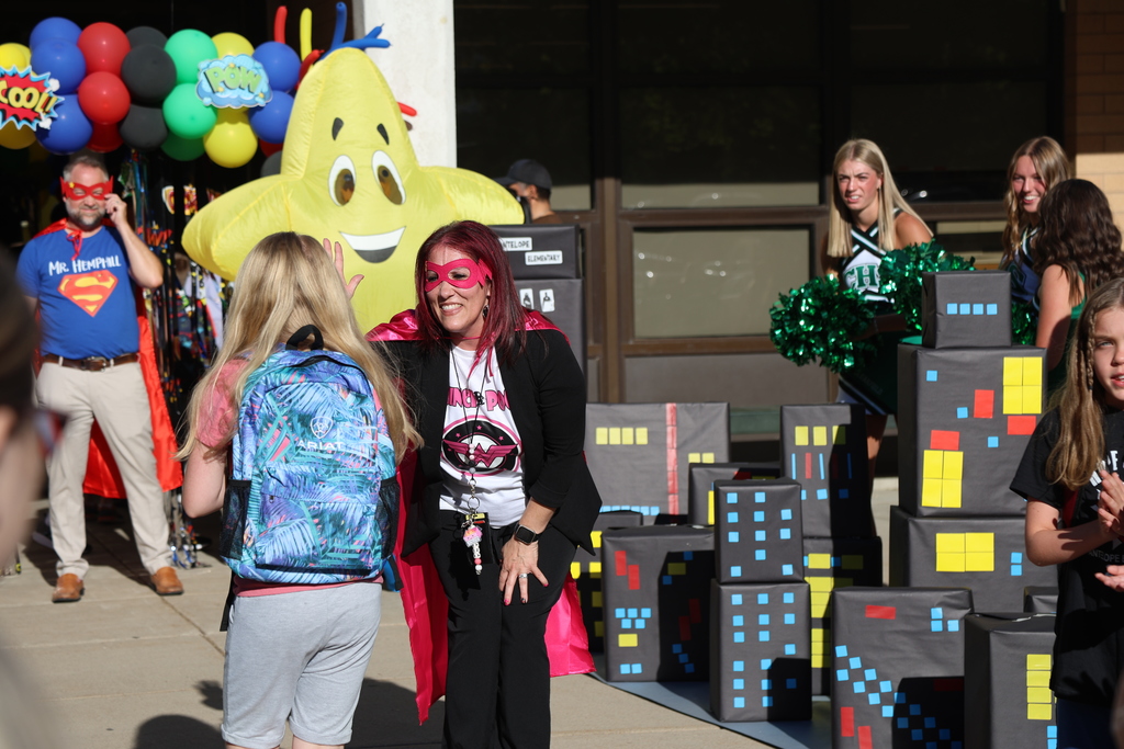 A principal high fiving a student. the principal is in a superhero costume.