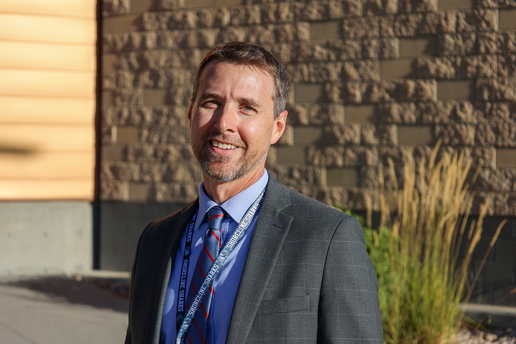 A principal smiles at the camera.