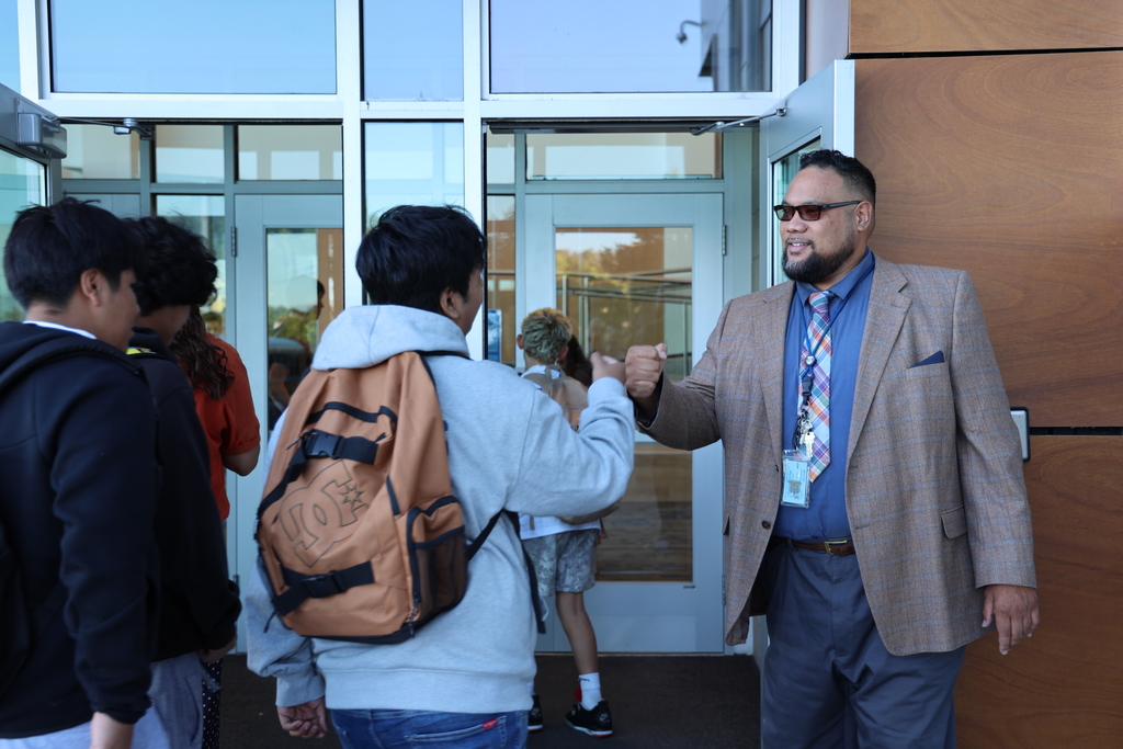 a principal knuckles students as they enter the building.