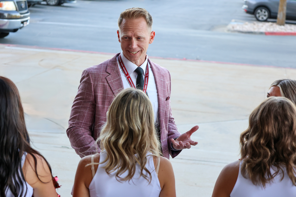 a principal smiling and talking to cheerleaders. 