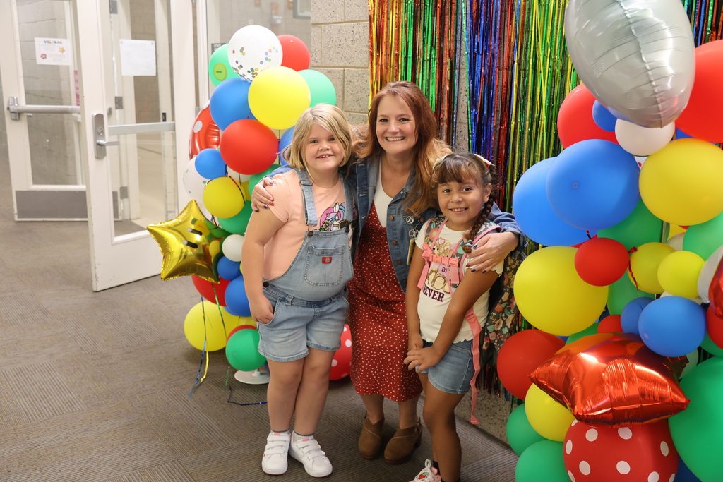 a principal standing with two students in front of a backdrop.